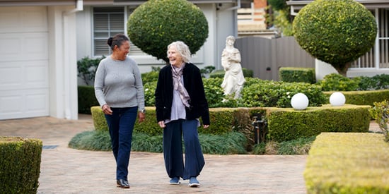 An older woman and a carer enjoy a stroll in the garden at HammondCare Strathearn House, an aged care home in the Upper Hunter Valley, NSW.
