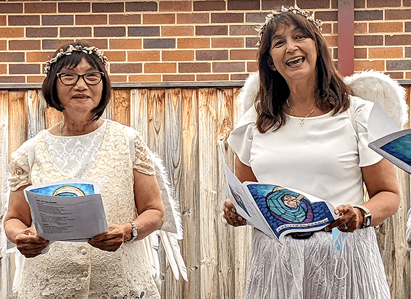 Kim Nguyen and Carol Blanchard singing carols for residents. They are dressed as angels