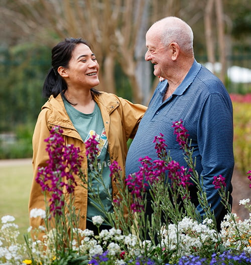 An older man and a carer enjoy a walk in the garden at HammondCare Hammondville, an aged care home in South Sydney, NSW.