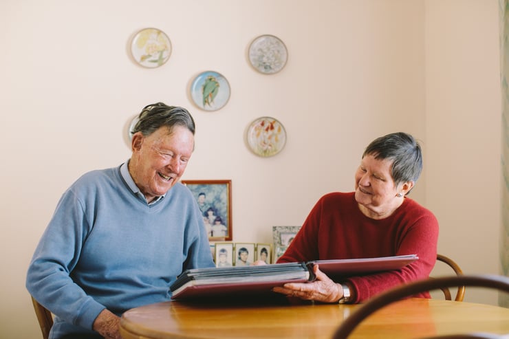 John sits with his Home Care carer, looking through a photo album