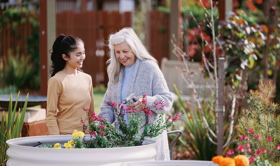 A woman and a carer walk through the garden at HammondCare Daw Park, an aged care home in Adelaide.