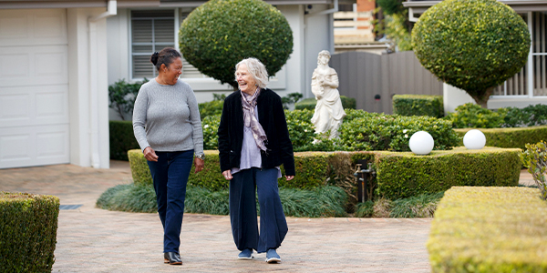 An older woman and a carer enjoy a stroll in the garden at HammondCare Strathearn House, an aged care home in the Upper Hunter Valley, NSW.