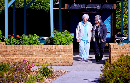 Two people enjoy a stroll in the garden at HammondCare Woy Woy, an aged care home in the Central Coast, NSW.